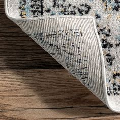 an area rug on top of a wooden floor with a white and blue design in the middle