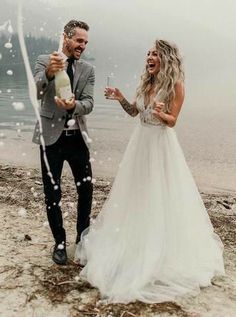 a man and woman standing on top of a beach next to the ocean with bubbles