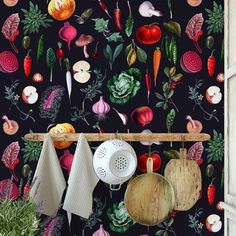 the kitchen wall is decorated with colorful vegetables and cooking utensils hanging from hooks