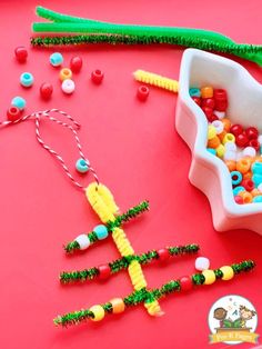 a bowl filled with candy and beads next to a plastic spoon on a red surface