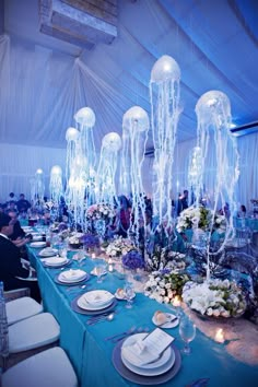 the tables are set with white plates and place settings for an ocean themed dinner party