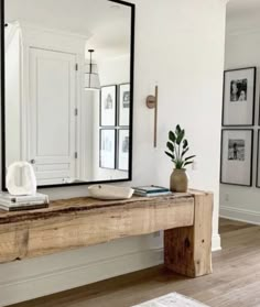 a large mirror sitting on top of a wooden table in front of a white wall