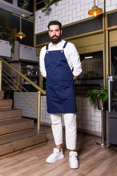 a man standing in front of some stairs wearing an apron and white shoes with his hands on his hips