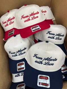 several hats in a cardboard box with stickers on the front and back, including from atlanta with love