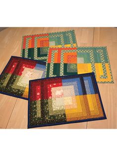 three quilted place mats sitting on top of a wooden floor