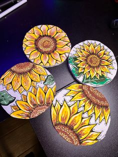 four sunflower coasters sitting on top of a black table next to a keyboard