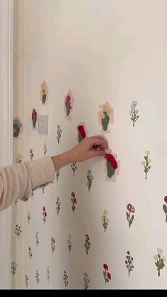 a woman is painting flowers on the wall