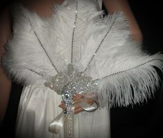 a woman in a white dress is wearing a feathered bridal gown and brooch