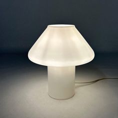 a white table lamp sitting on top of a gray floor