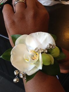 a woman's hand holding a white flower with green leaves and bells on it