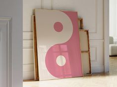 a pink and white painting sitting on top of a hard wood floor next to a door