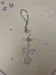 a purple and white necklace hanging from a hook on a wall with butterflies painted on it