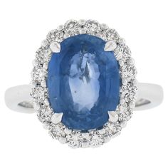 an oval shaped blue sapphire surrounded by white diamonds in a halo style setting on a diamond band