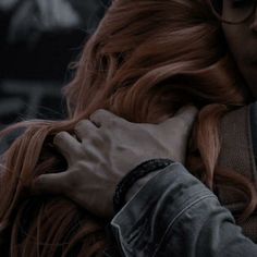 a close up of a person with long red hair and glasses holding their hands together