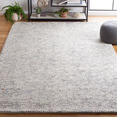 a living room area with a rug, chair and bookshelf on the floor