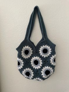 a crocheted bag hanging on the wall with sunflowers attached to it