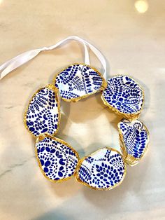 a blue and white flowered bracelet on a marble counter top with a white ribbon around it