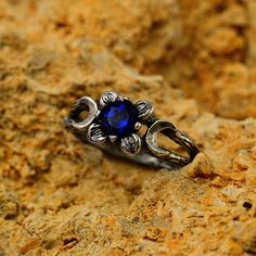 a ring with a blue stone in the middle on top of some rocks and dirt