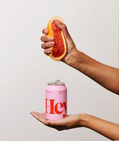 a person holding a can of soda and grapefruit