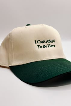 Introducing the I Can't Afford To Be Here" Trucker Hat, a witty and lighthearted accessory for your everyday adventures. This hat features a beige body adorned with bold dark green embroidery that humorously declares "I Can't Afford To Be Here." The dark green bill adds a contrasting touch, while the adjustable back ensures a comfortable fit. On the back of the hat, you'll find the embroidered phrase "The Happiest :)" to add a touch of whimsy. Perfect for those who appreciate humor and want to a