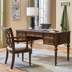 a wooden desk with a laptop on top of it next to a chair and lamp