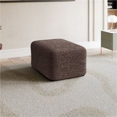 a square footstool sitting on top of a carpeted floor next to a wall