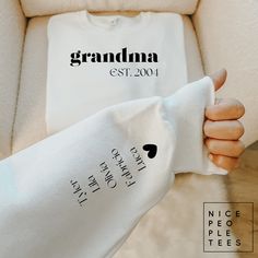 a woman's hand holding up a white t - shirt that says grandma est 2009