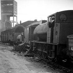 black and white photograph of an old train on the tracks in front of some buildings