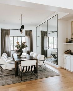 the dining room table is surrounded by white chairs and black framed mirrors on the wall