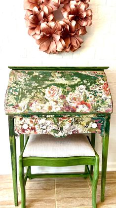 a green painted bench with a wreath on the wall above it and a chair in front of it