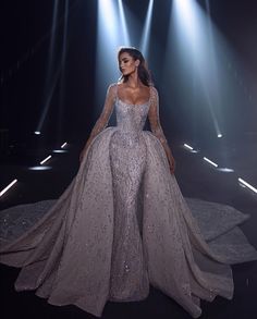 a model walks down the runway in a gown with long sleeves and sequins