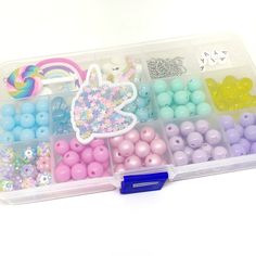 a plastic container filled with lots of different colored beads and decorations on top of a white table