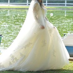 a woman in a wedding dress is standing by the water