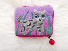 a small purse with an image of a cat on the front and side, sitting on a white fur surface