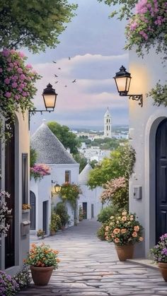 an alley way with potted plants and flowers on either side that leads to a clock tower