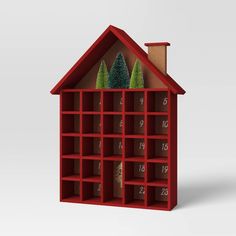 a red bookcase filled with lots of books next to a small christmas tree on top of it