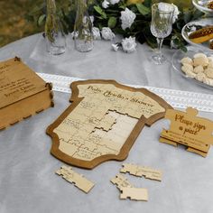 a table topped with lots of wooden pieces next to wine glasses and plates filled with food