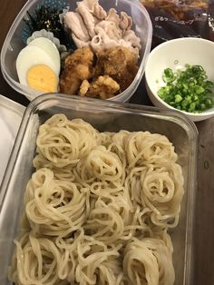 there are many different types of food in the trays, including noodles and chicken