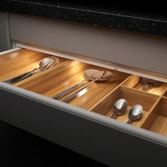 an open drawer with utensils and spoons in it