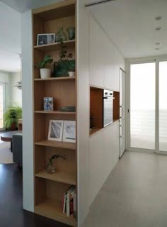 an open book shelf in the corner of a room with sliding glass doors and potted plants