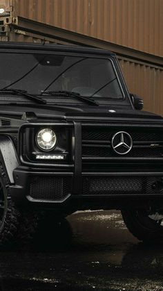 a black mercedes g - class parked in front of a building