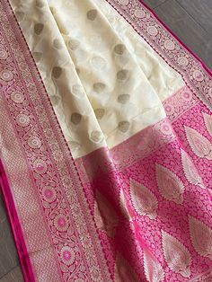 Gorgeous handloom soft banarasi silk saree in off white. Dull gold silk thread motifs are woven all over the saree. Magenta border and anchal is intricately woven with zari as well. Comes with a contrast magenta blouse piece. This saree is perfect for festival and formal occasions. Saree is 6+ yards long 45 inches wide Blouse piece is 37 inches Care: Dry clean only Disclaimer: Color and shade of saree may vary in the pictures than the actual item. There might be slight weaving irregularities since the product is woven by hand. Off White Silk Saree For Festivals, Off-white Silk Saree For Festivals, White Tussar Silk Saree With Traditional Patterns, White Silk Handloom Dupatta, White Silk Handloom Traditional Wear, Off White Tussar Silk Traditional Wear, Traditional Off White Tussar Silk Saree, Off White Traditional Tussar Silk Wear, Traditional Off-white Tussar Silk Saree