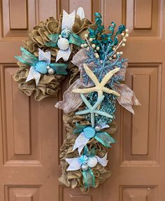 a wreath with starfishs and seashells hanging on a door