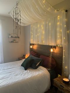 a bed with white sheets and lights on the headboard is in front of a window