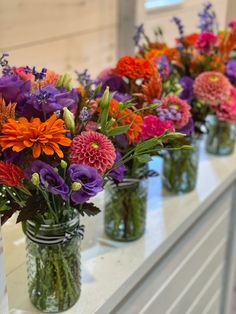 several vases filled with colorful flowers sitting on a counter