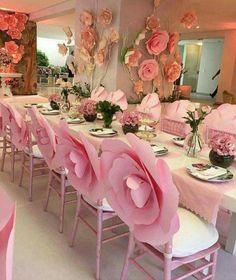 the table is set with pink flowers and place settings for guests to sit down at