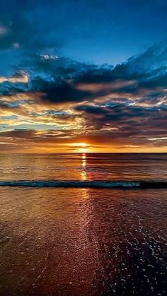 the sun is setting over the ocean with clouds in the sky and water on the beach