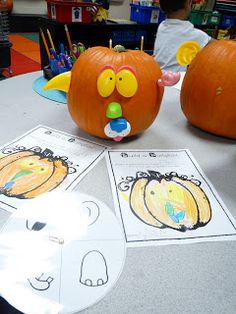 two pumpkins with faces on them sitting on a table in front of a cd