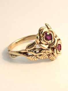 Two detailed roses make up this elegant ring, their stems entwining and forming the band. The ring is cast in solid 14K gold and two 3 mm rubies are set in the center of each rose. Indulge yourself or someone special in this sparkling bouquet. We will contact you to let you know if we have your chosen ring size in stock or when to expect shipment. All Marty Magic Jewelry is packaged in a beautiful ring box embossed with the gold foil Marty Magic dragon logo. Perfect for any occasion! Designed in Vintage 14k Gold Flower Ring, Vintage Rose Gold Ruby Promise Ring, Vintage Rose Gold 14k Gold Flower Ring, Vintage 14k Rose Gold Flower Ring, Vintage 14k Gold Flower Ring For Formal Occasions, Formal Yellow Gold Flower Ring With Rose Design, Formal Rose Flower Shaped Rings, Formal Rose Flower Rings, Formal Rose Colored Flower Shaped Rings