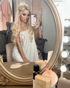 a woman taking a selfie in front of a mirror with soaps and makeup